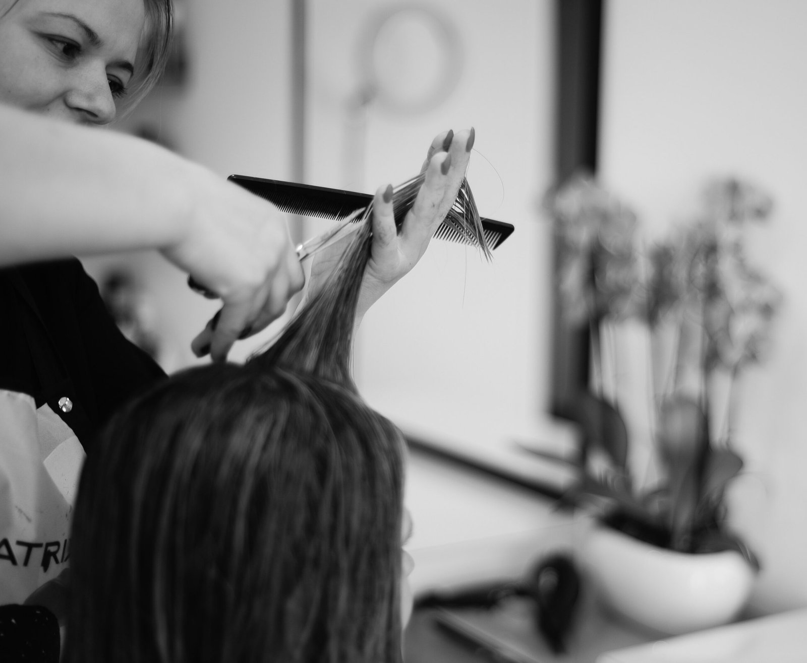 a woman cutting another woman's hair in a salon